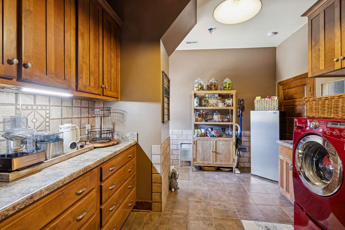 This is the side entrance/foyer with tile floor, additional cabinetry and laundry area. The little refrigerator and the washer/dryer do not remain with the home.