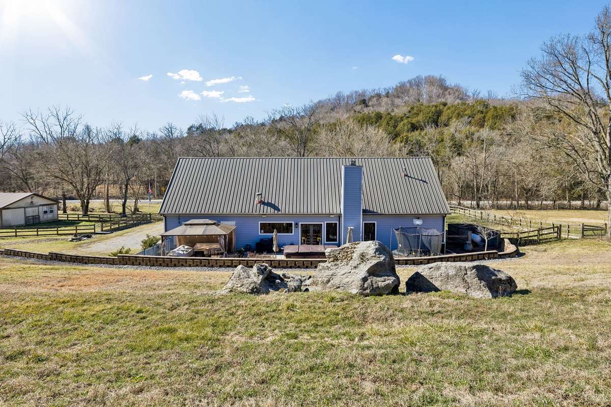 A great view of the back of the home with the metal roof, the retaining wall, and the huge boulders that sit on the hill!