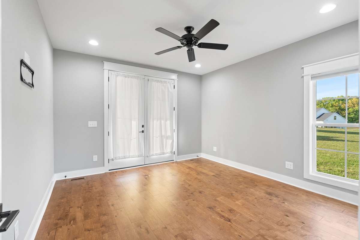 Spacious primary suite with hardwood floors, ceiling fan, and private access to the screened porch.