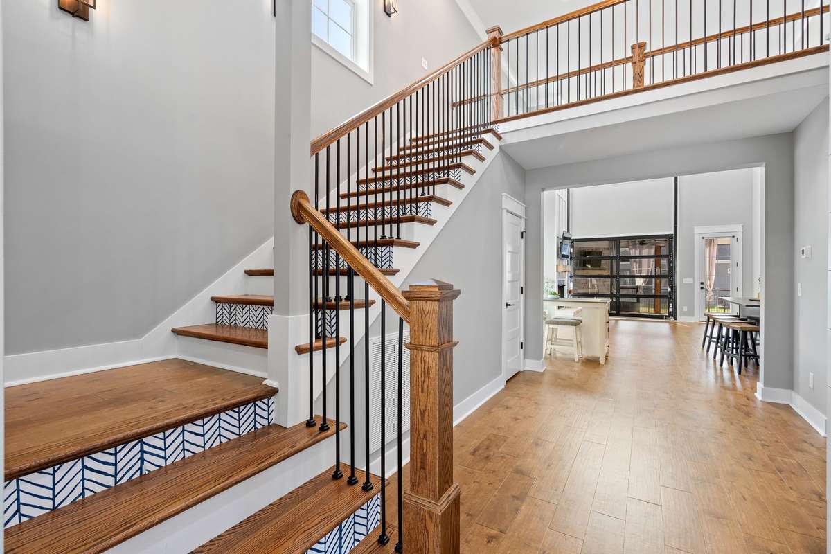 Elegant staircase with wood treads and iron balusters creates a striking first impression.