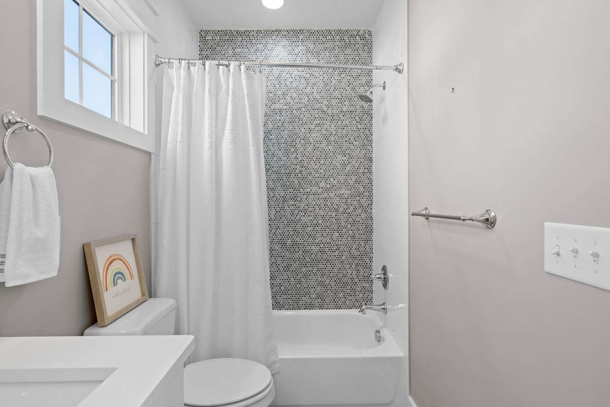 Bright and functional guest bath with tub/shower combo and stylish tile surround.