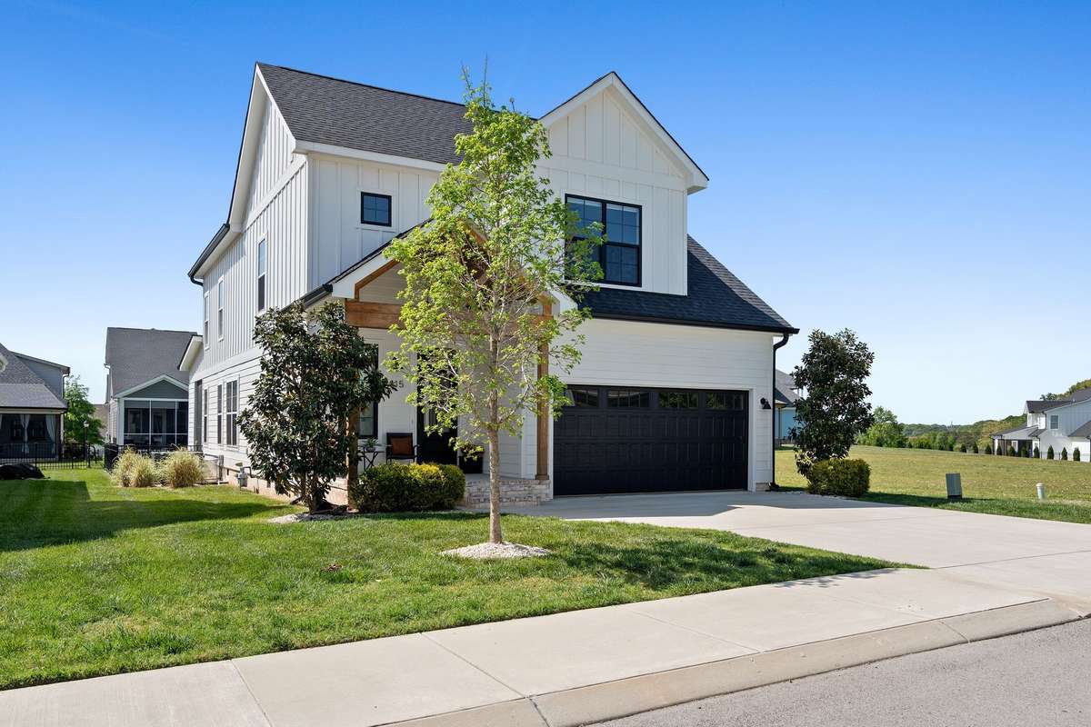 Side view showcasing the home’s scale, manicured lawn, and desirable lot setting.
