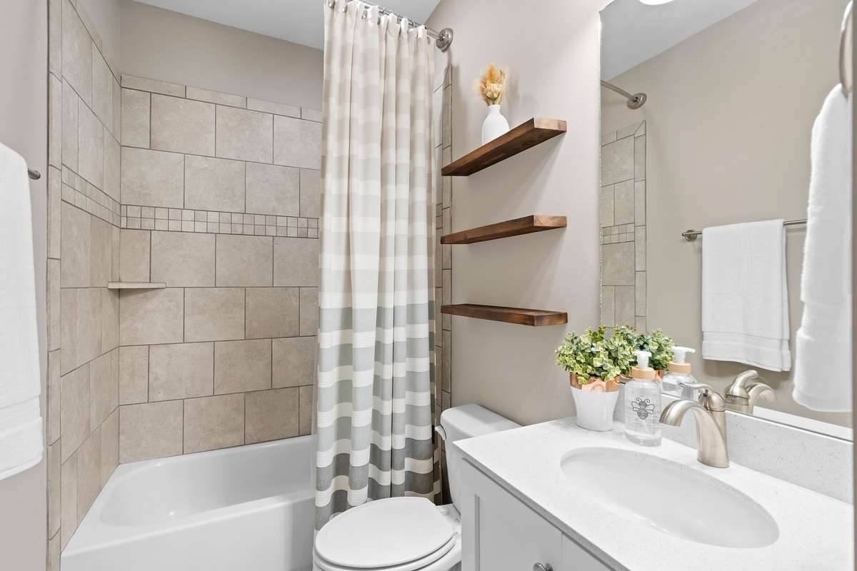 Secondary bathroom with tiled tub/shower combination and modern vanity.