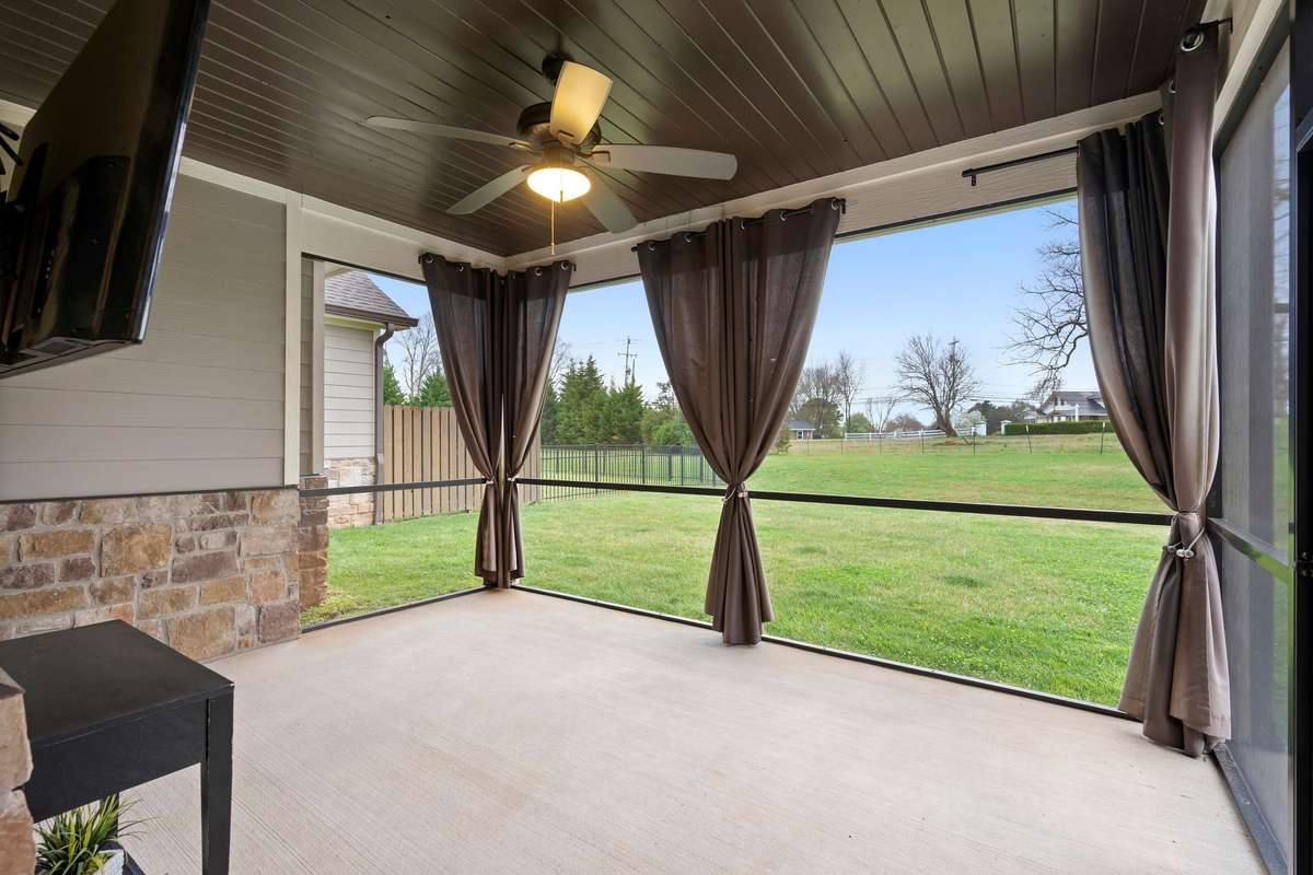 Screened-in covered patio with ceiling fan and outdoor TV space, perfect for relaxing or entertaining.