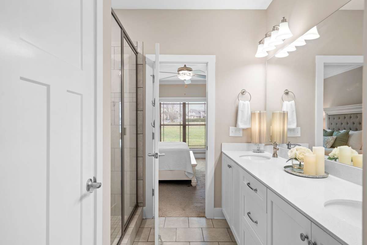 Primary suite bath with dual sinks, large mirror, and private access to the bedroom.