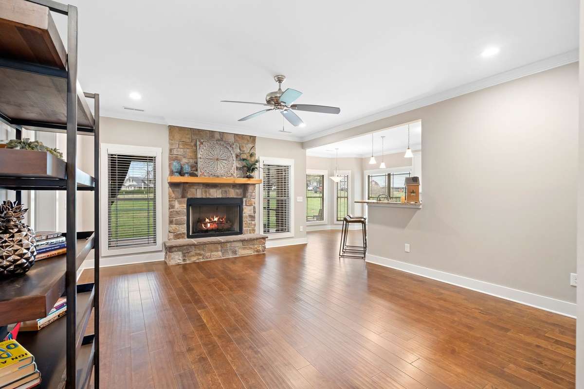 Light-filled living room with hardwood floors and beautiful stone fireplace centerpiece.