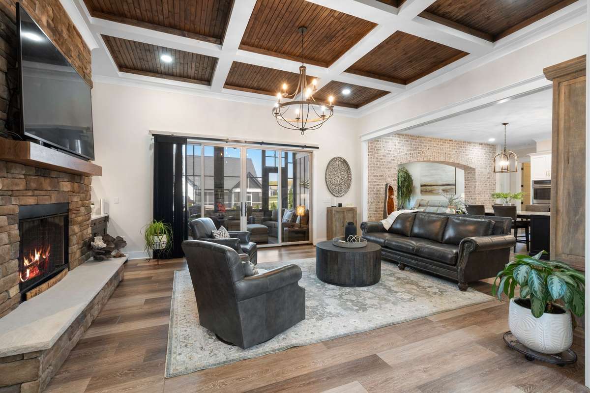 Open-concept living area with coffered wood ceiling, gas fireplace, and seamless flow to outdoor living.