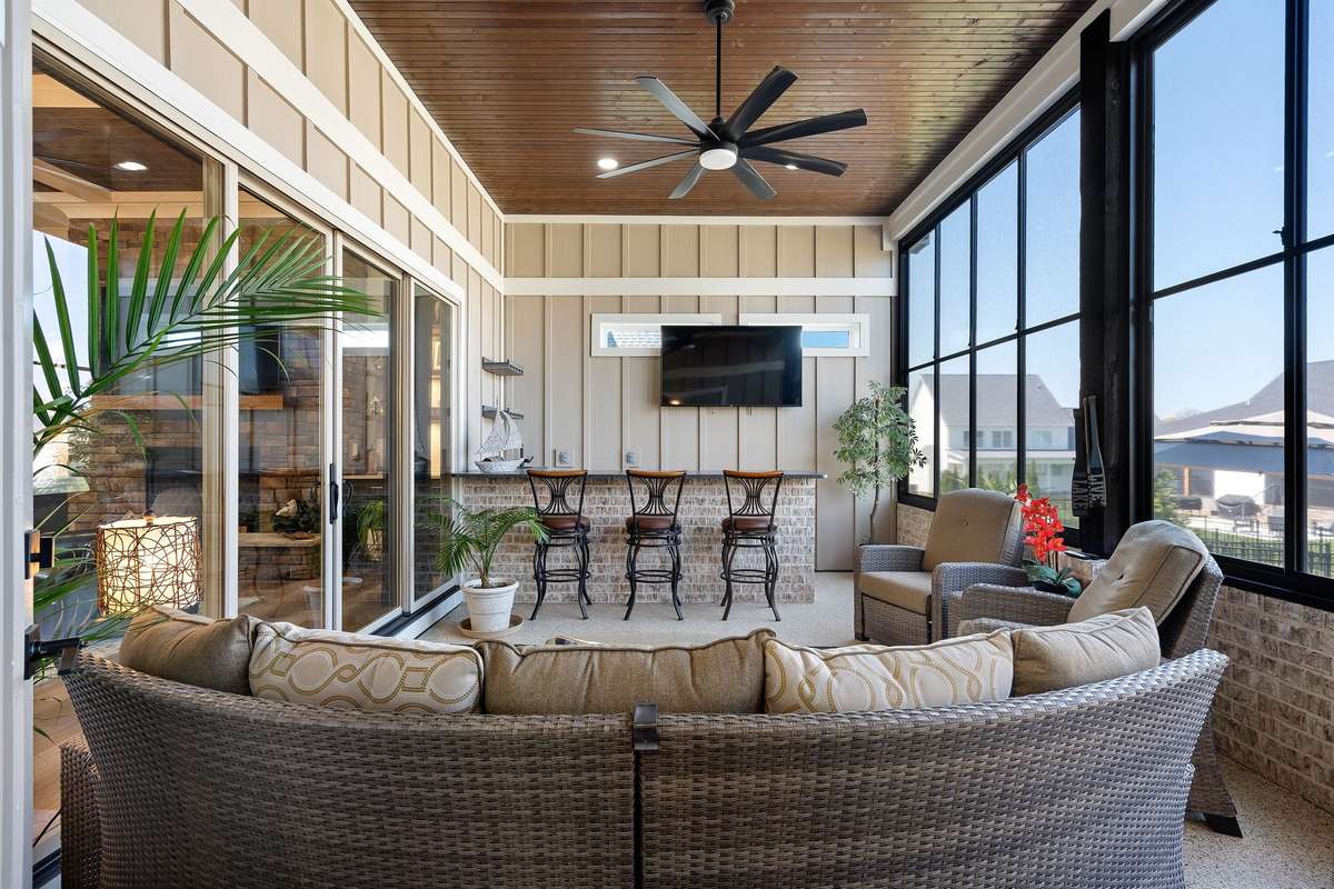 Expansive screened-in porch with wood-paneled ceiling, ceiling fan, and outdoor bar—ideal for year-round entertaining.