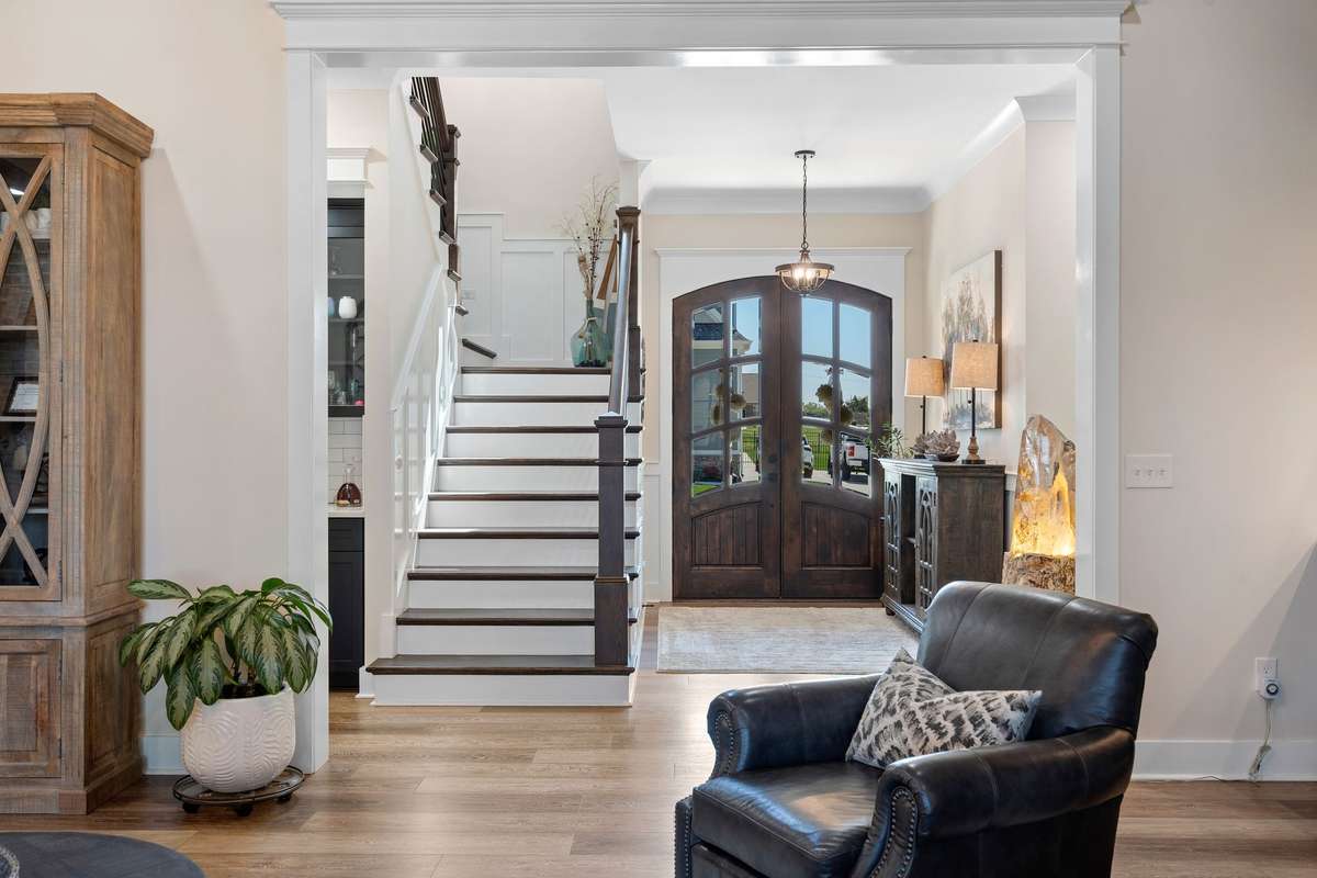 Welcoming entry with custom wood doors, staircase, and thoughtful architectural details.