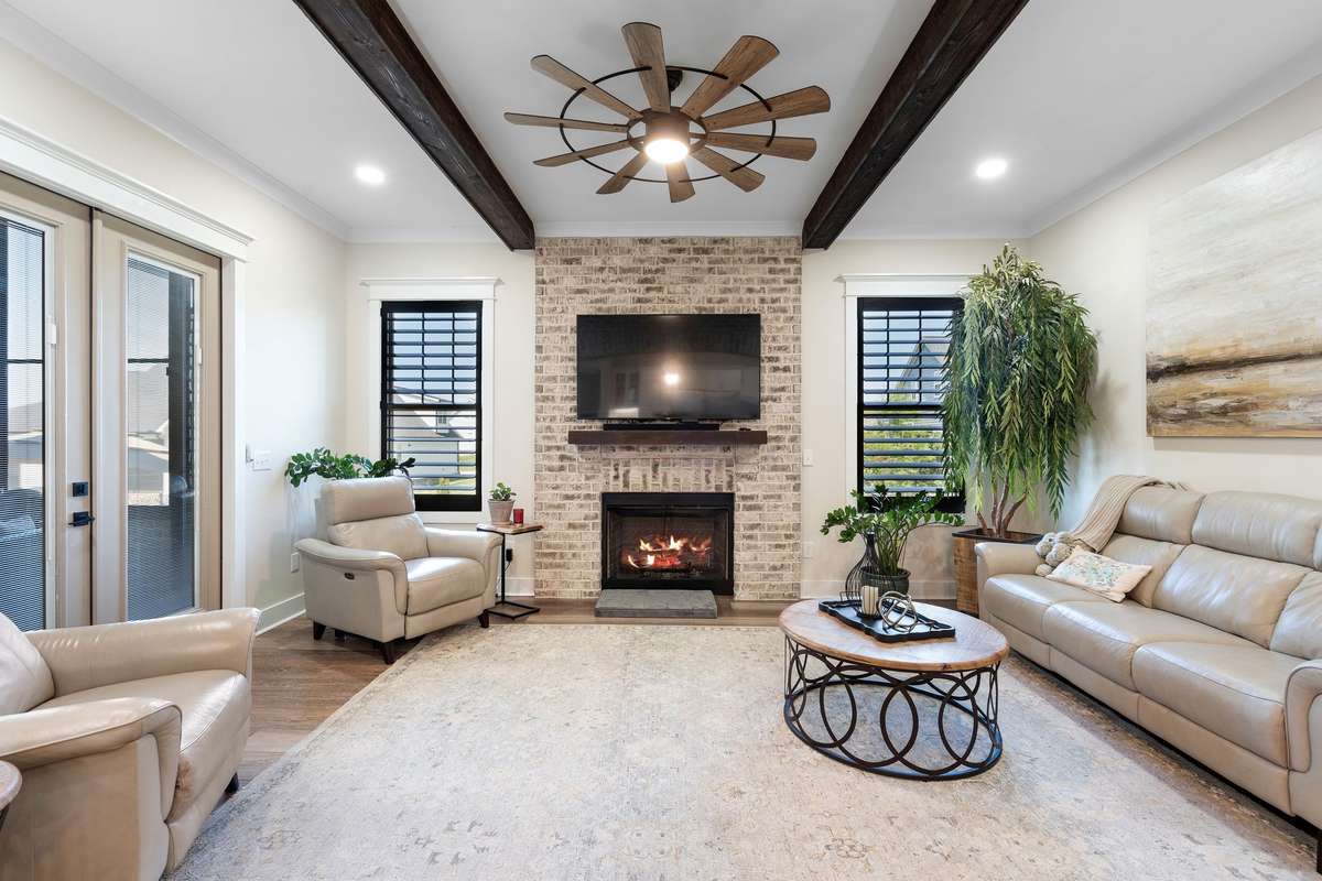 Inviting living room featuring exposed beams, brick fireplace, and abundant natural light.