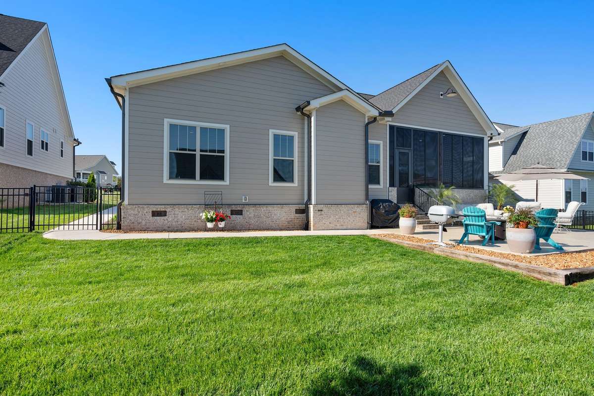 Beautiful rear elevation with large screened porch, professionally landscaped yard, and extended outdoor living space.