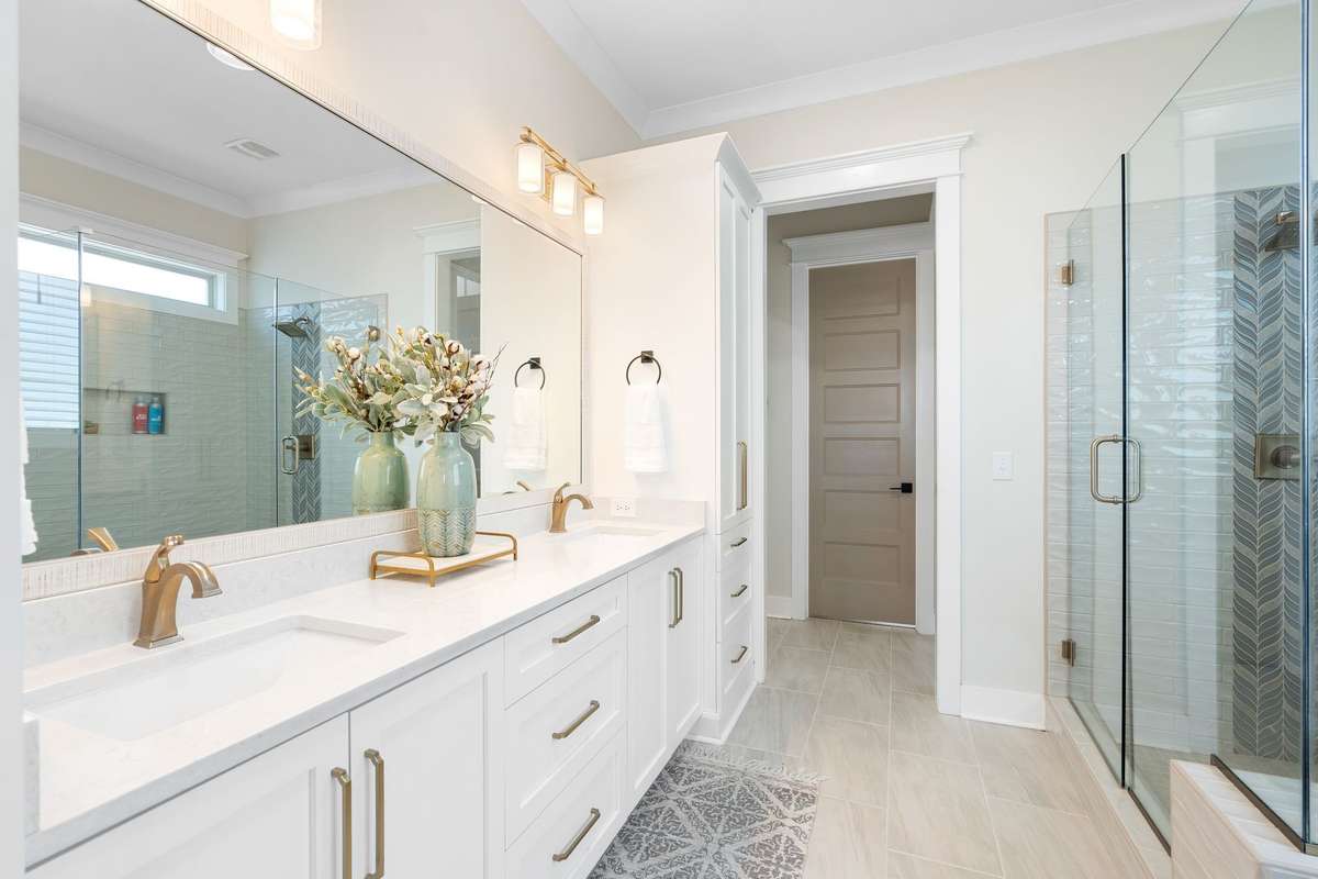 Spa-like primary bath featuring double vanities, quartz countertops, and designer lighting.