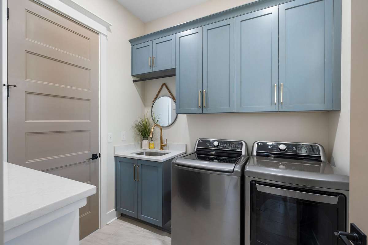 Well-appointed laundry room with cabinetry, utility sink, and ample workspace