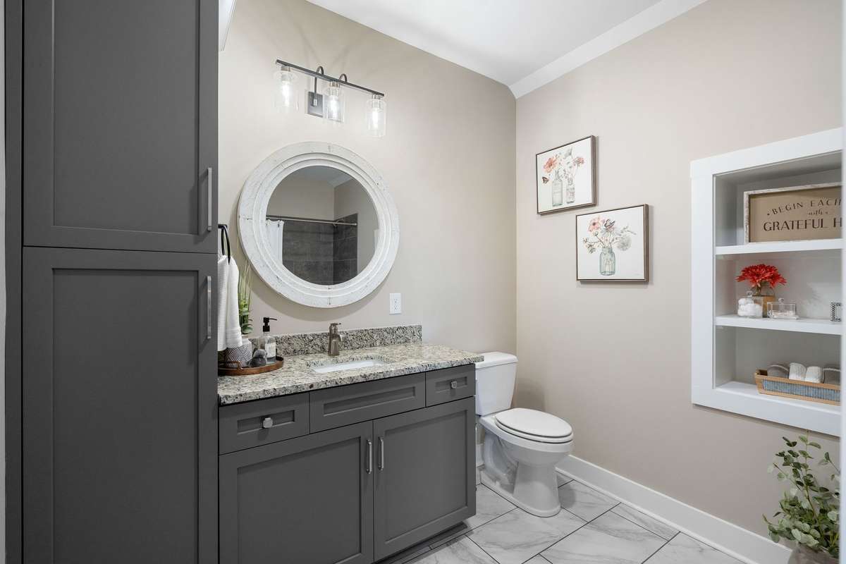 Stylish guest bath featuring granite countertops, custom cabinetry, designer lighting, and a tiled walk-in shower