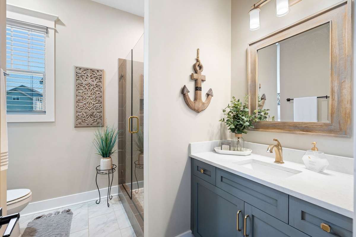 Stylish full bath with quartz countertops, designer fixtures, and a tiled walk-in shower.