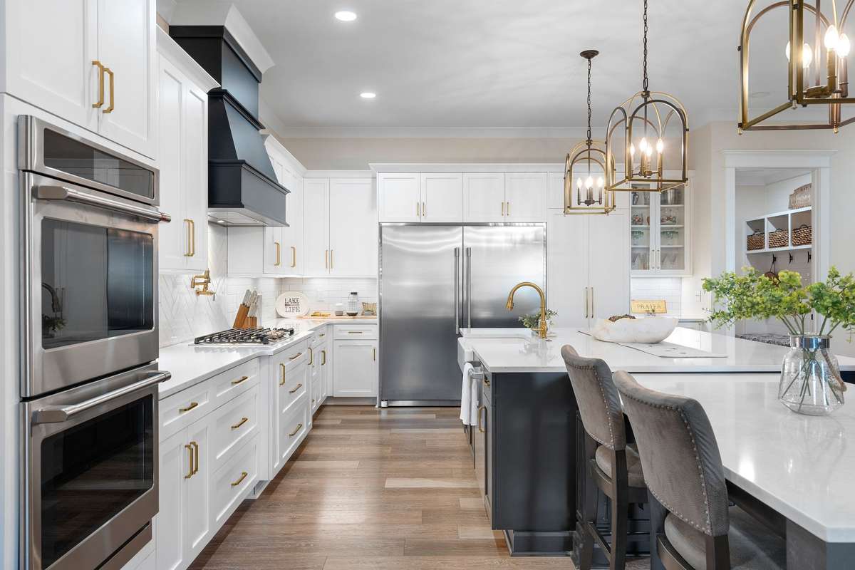High-end finishes including stainless steel appliances, gas cooktop, double ovens, and custom vent hood.