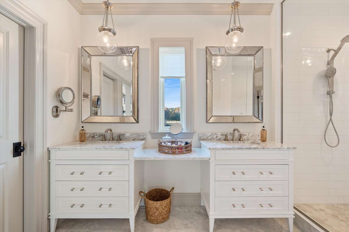 Primary bathroom with double vanities, center makeup station, and window for natural lighting, Large walk in closet with ELFA shelving