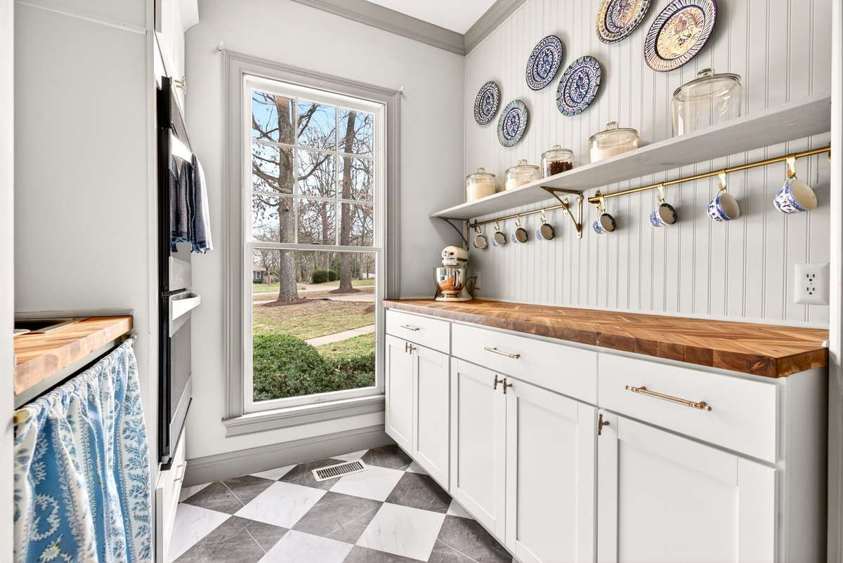 Scullery - Double Ovens, wood paneling, checkered floors, a dedicated bar sink for a coffee bar setup, and a large pantry closet.