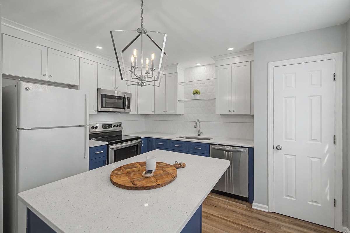 New kitchen cabinets with crown molding in a bright white complement the granite countertop, which features flecks of stainless steel.