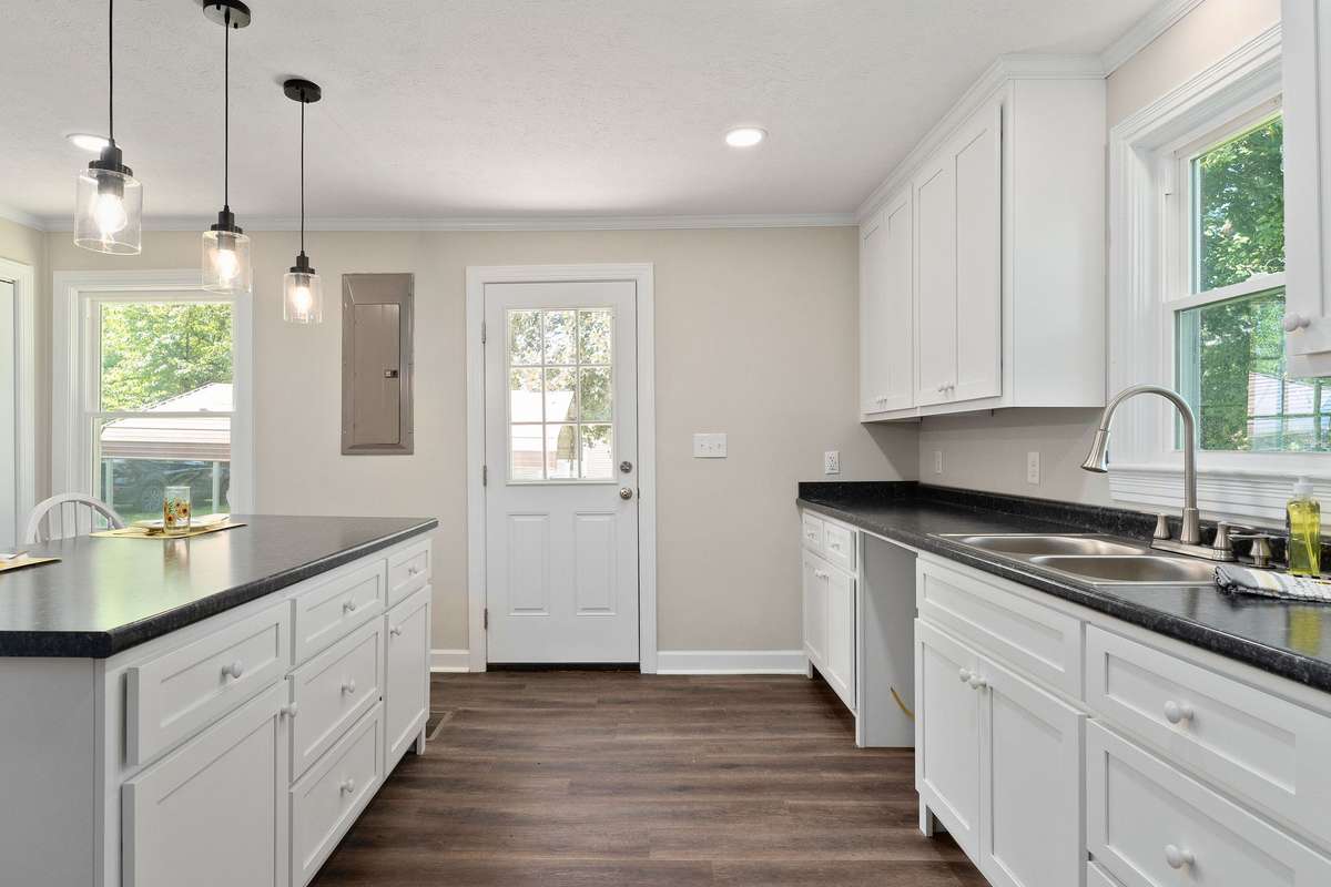 The new kitchen features new flooring, paint, backdoor, windows, and cabinets with new counter tops.
