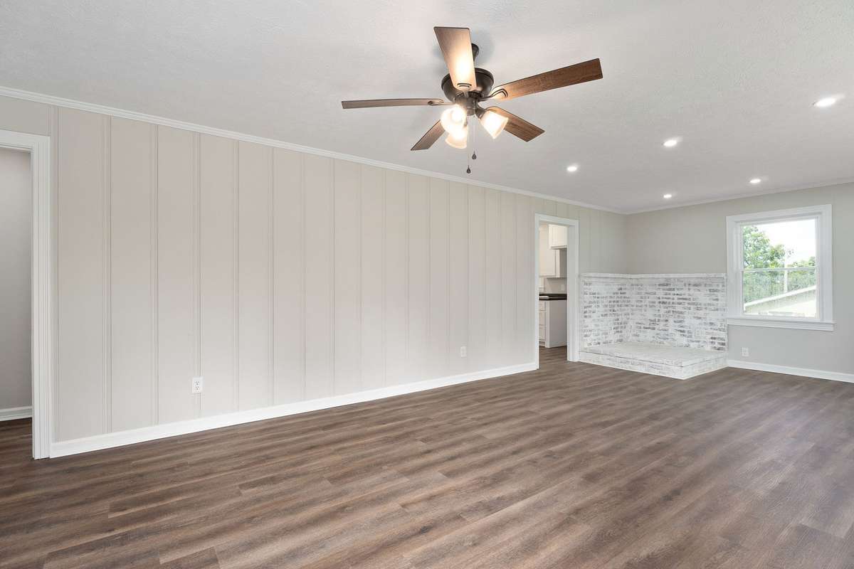 The freshly painted living room has laminate flooring, can lights, and a ceiling fan.