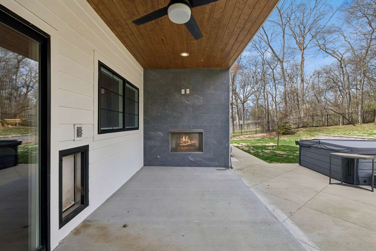 Outdoor living features a covered porch with second gas fireplace, built-in dog door and overlooks beautiful rolling backyard with oversized spa.
