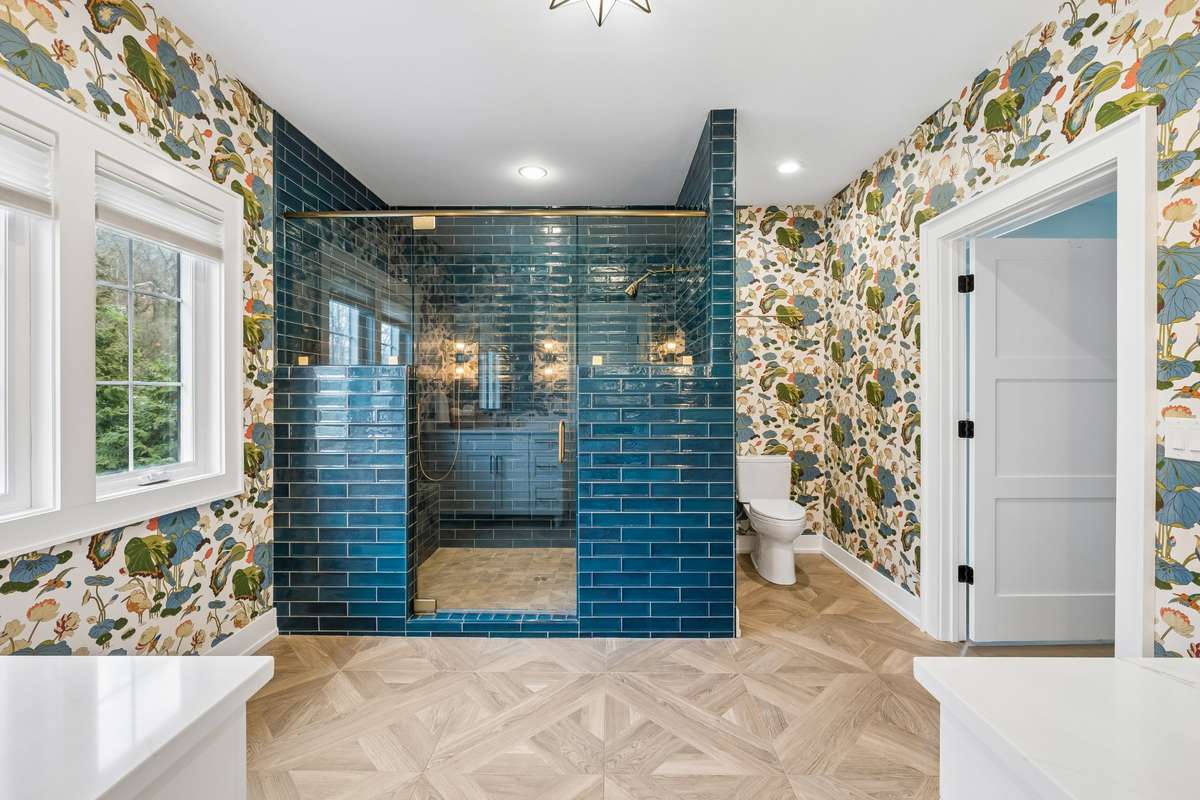 Oversized primary walk-in shower, double vanities and beautiful vibrant wallpaper make this resort-like bathroom a main draw.