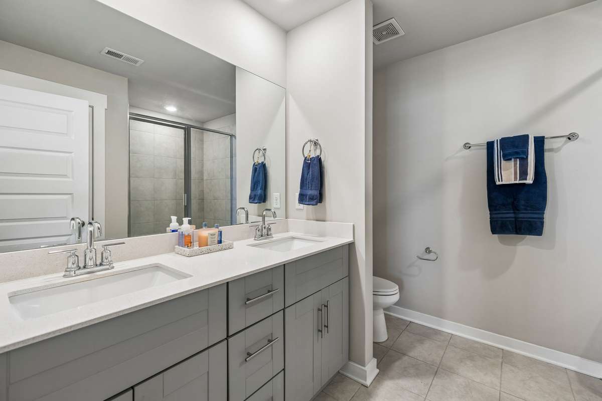 Primary full bath with double vanity, shower with glass door and linen closet