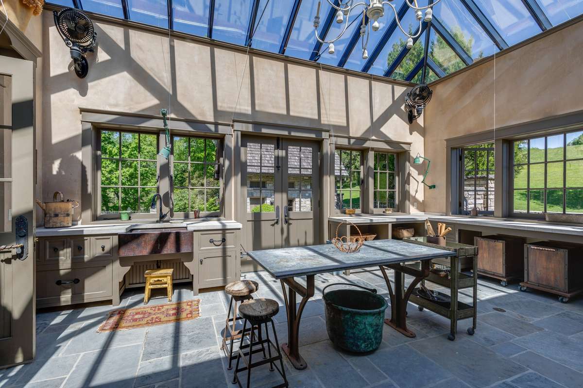 The greenhouse is one-of-a-kind, stone floors and countertops, a half bath, mini kitchen, and an abundance of windows make this a flexible space even for the non-gardeners