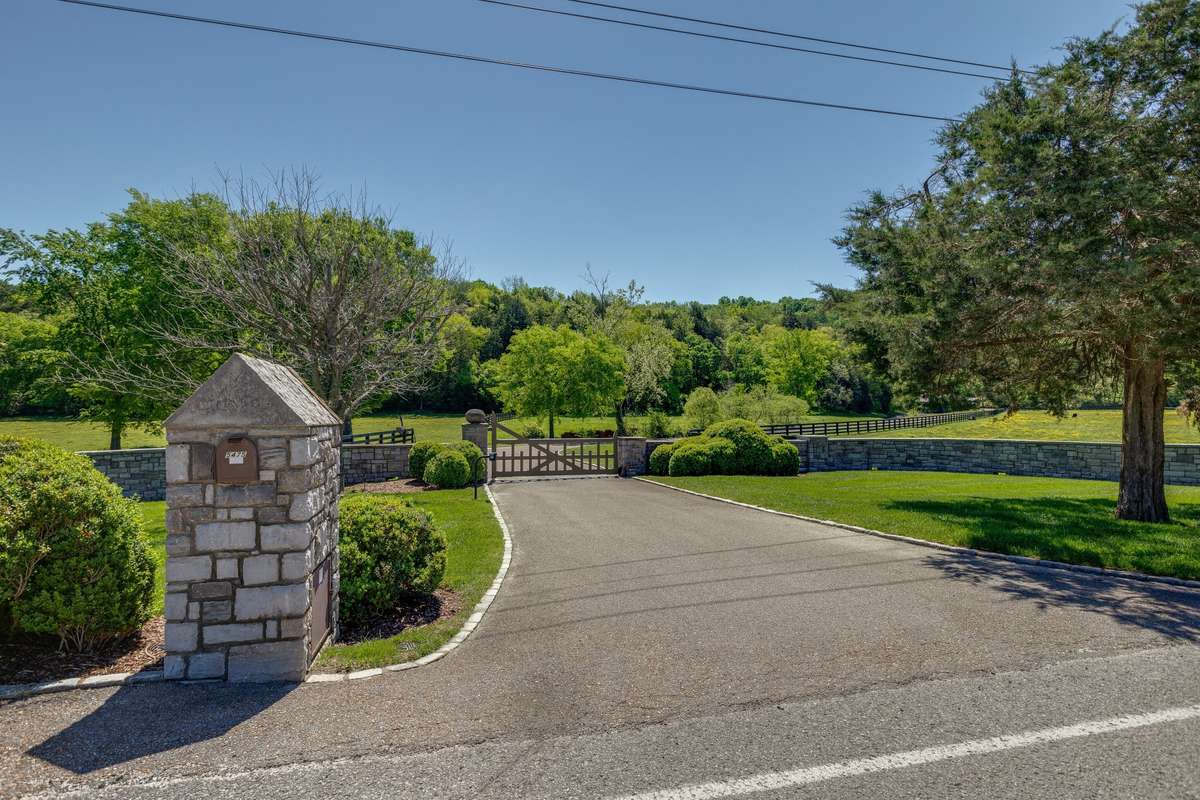 The entrance features stonework and electric gate