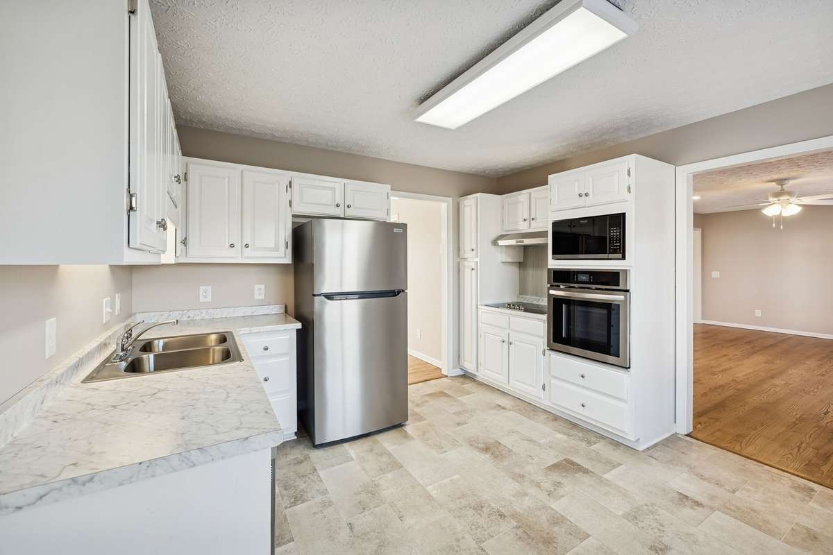 Bright kitchen with white cabinetry and stainless steel appliances...