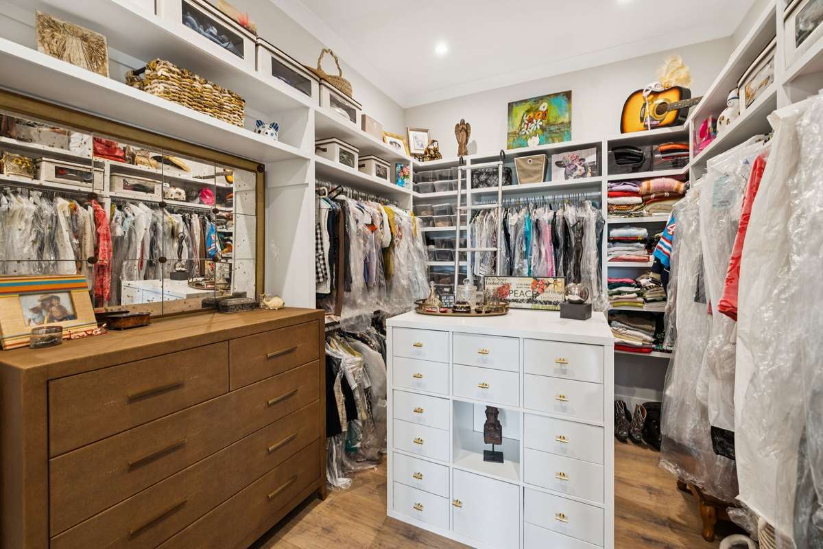 Spacious walk-in closet with custom shelving, built-in drawers, and ample hanging space. Thoughtfully designed layout offers exceptional storage and organization for a well-appointed primary suite.