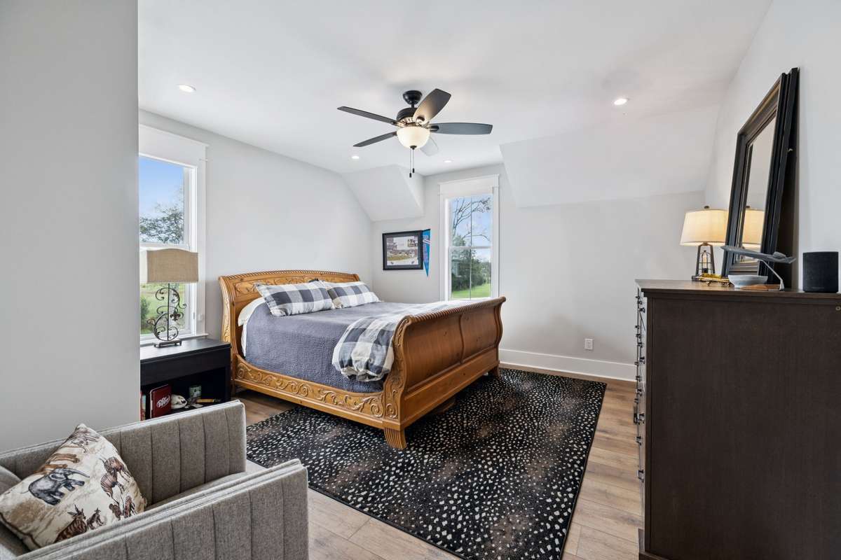 Light-filled secondary bedroom with vaulted ceilings, recessed lighting, and multiple windows overlooking the property. Spacious layout with wide-plank floors and generous closet space, perfect for guests or family.