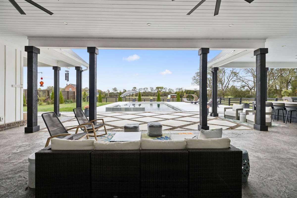 Covered outdoor living area with brick fireplace and ceiling fans, designed for year-round entertaining.