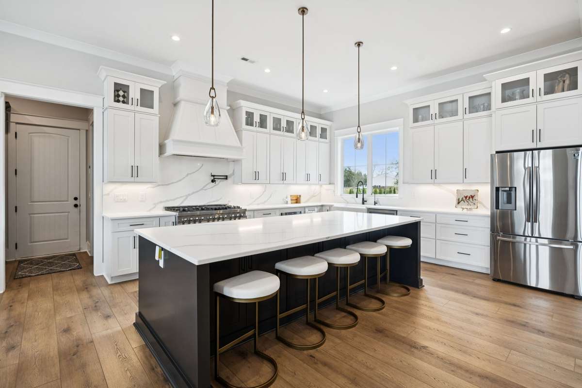 Chef’s kitchen with oversized island seating, quartz countertops, custom cabinetry, and professional-grade range. Thoughtful storage, glass-front upper cabinets, and a walk-in pantry combine style and function for everyday living and entertaining.