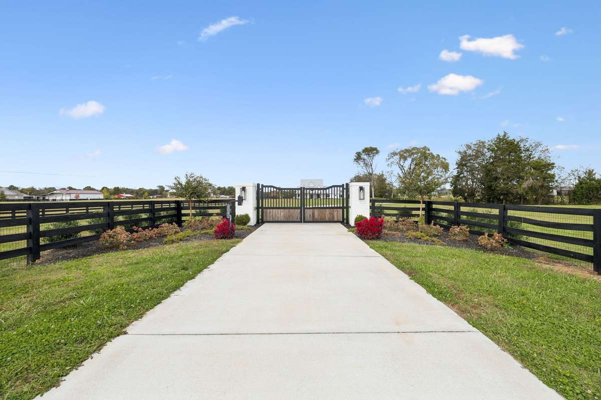 Private gated entrance with concrete drive and black board fencing creates a grand first impression. Landscaped entry with custom columns and automatic gate offers security, privacy, and a refined approach to this fully fenced countryside estate.