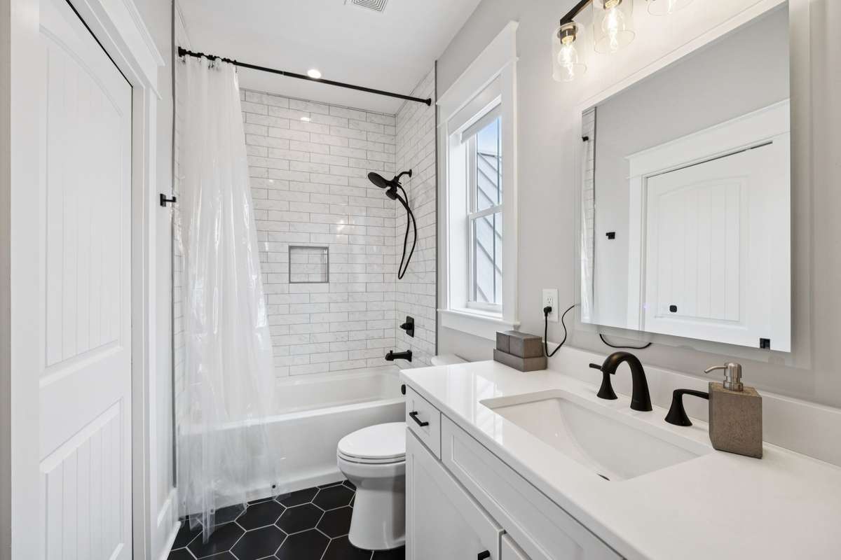 Well-appointed full bath featuring a tub/shower combination with subway tile surround, matte black fixtures, quartz vanity countertop, and timeless finishes throughout.