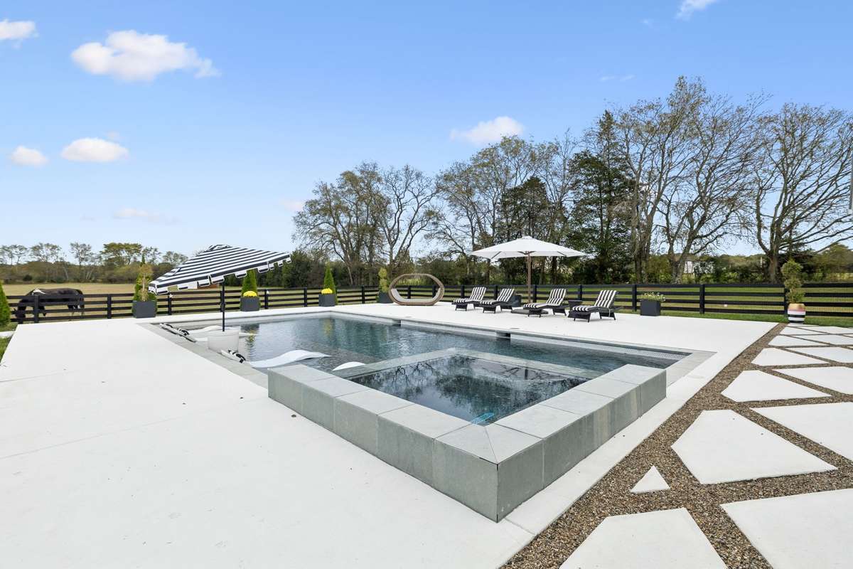Private fenced backyard showcasing the pool, outdoor living spaces, and surrounding acreage.