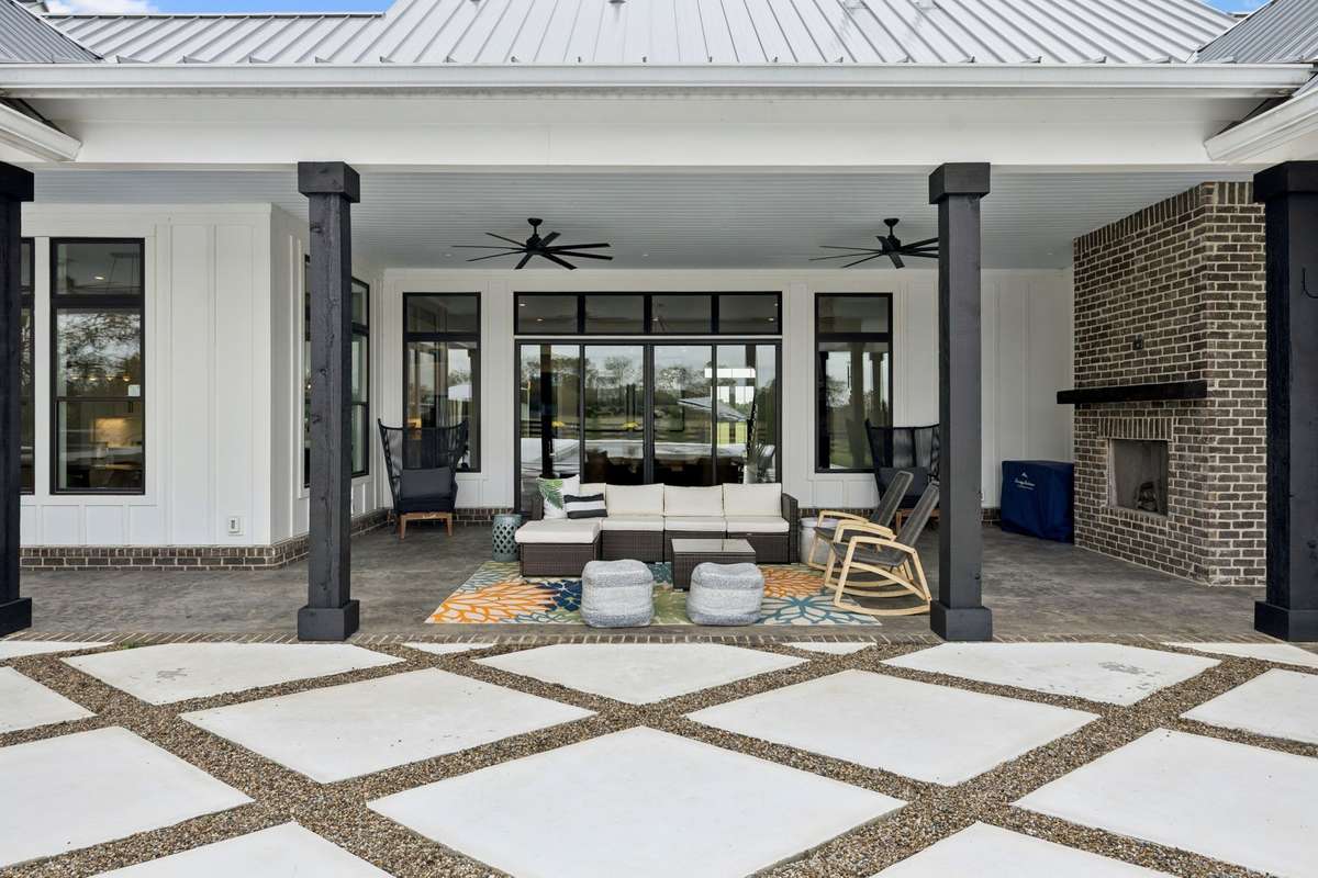Covered outdoor living area with brick fireplace and ceiling fans, designed for year-round entertaining.