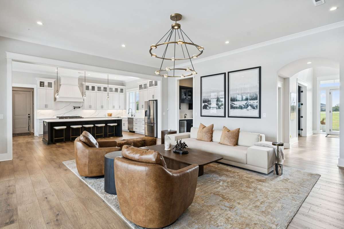 Seamless open-concept design connects living, dining, and kitchen spaces. Oversized island with seating anchors the kitchen, while wide-plank floors and neutral finishes create a cohesive setting ideal for entertaining and everyday comfort.