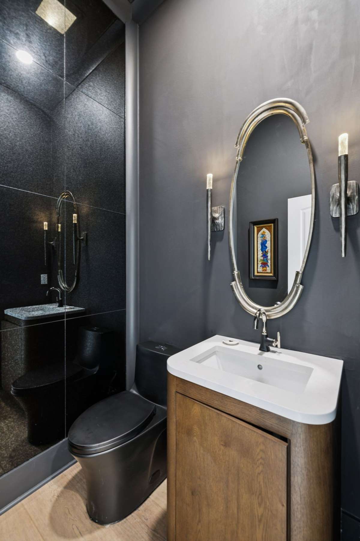 Main level half bath featuring a designer vanity, statement mirror, and dramatic tile shower. A stylish and convenient space for guests, thoughtfully designed with upscale finishes and modern fixtures.
