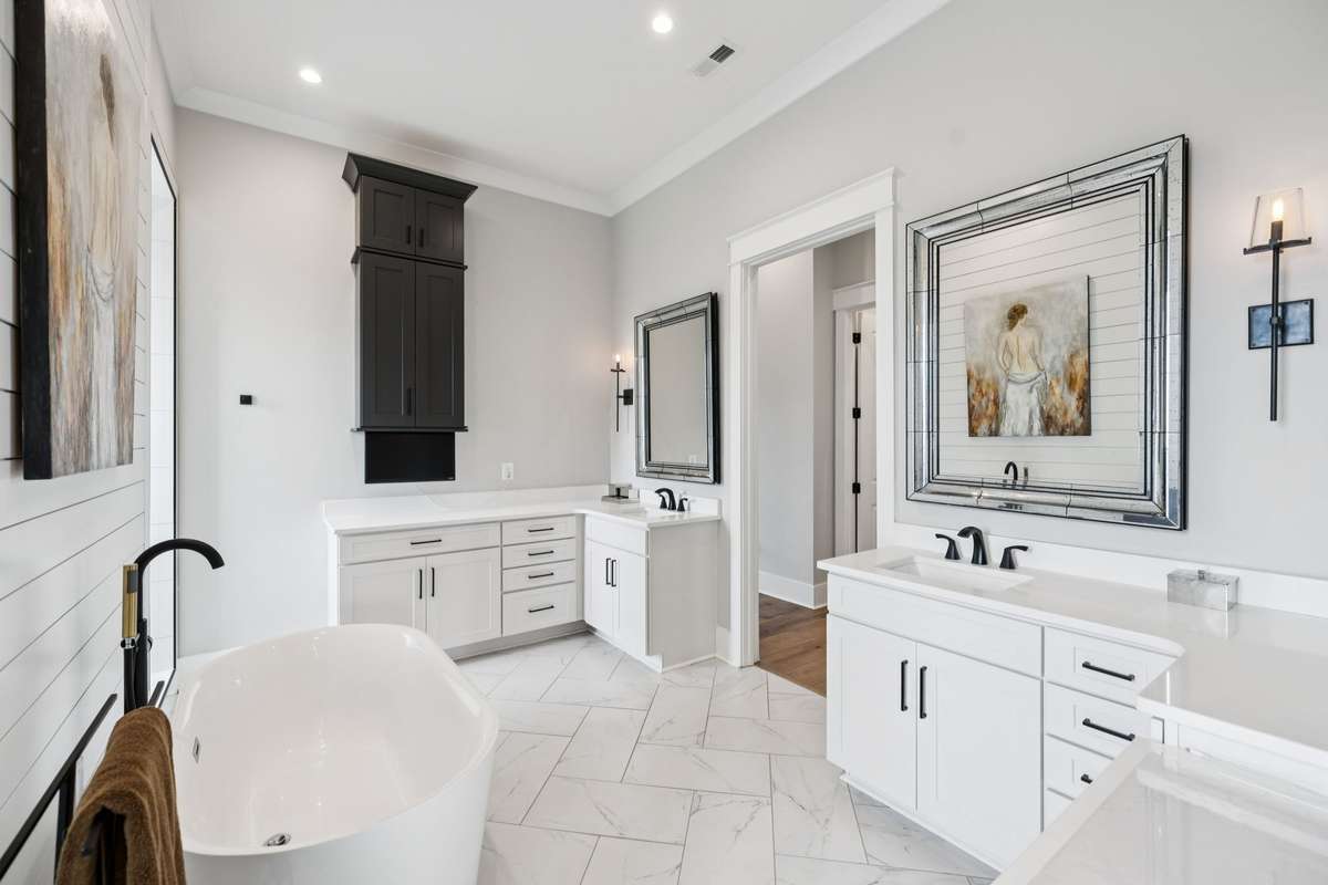 Spa-inspired primary bath featuring a freestanding soaking tub, dual vanities, and custom cabinetry. Light, airy finishes and thoughtful design create a serene retreat for daily routines and relaxation.