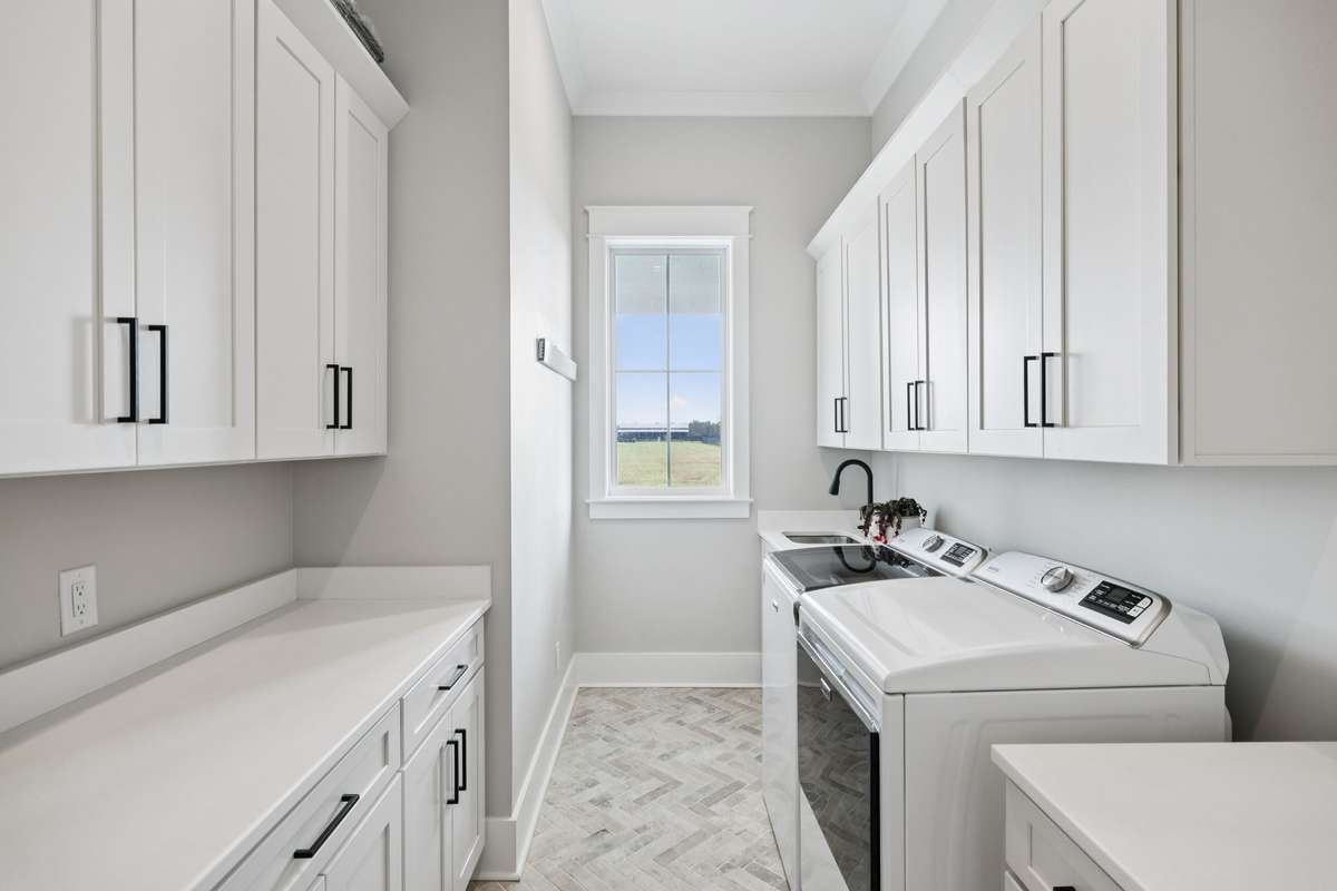 Dedicated laundry room with built-in cabinetry, folding counter, and utility sink. Abundant storage and natural light create a bright, functional space designed to simplify everyday living.