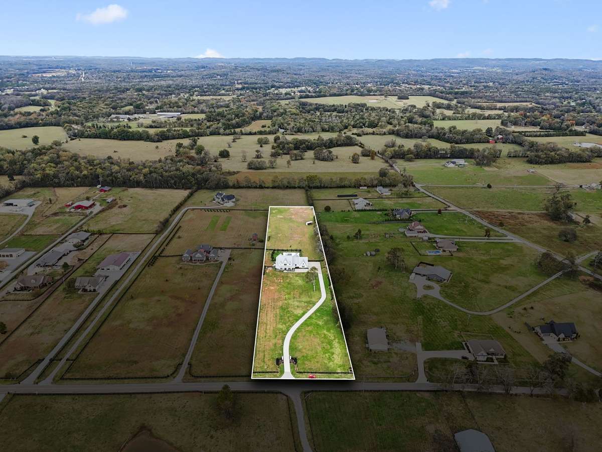 Aerial overview highlighting the full depth of the property, long private drive, and expansive acreage.