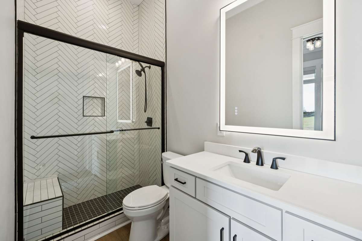 Well-appointed secondary bath featuring a tiled walk-in shower with glass enclosure, modern fixtures, and a sleek vanity with ample storage. Designed with clean lines and timeless finishes for everyday comfort.