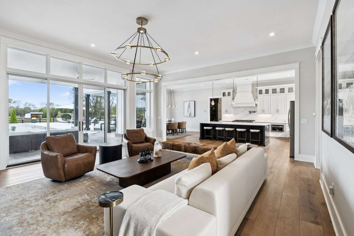 Open living and kitchen layout designed for effortless entertaining. Expansive windows and sliding doors frame pool views, while the oversized island anchors the kitchen and keeps guests connected to the main gathering space.