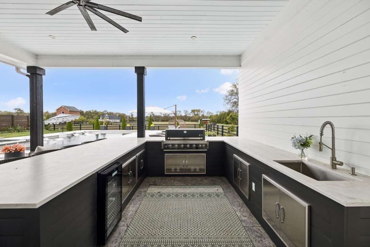 Fully equipped outdoor kitchen with built-in grill, prep space, sink, and beverage cooler — seamlessly connected to the pool terrace.