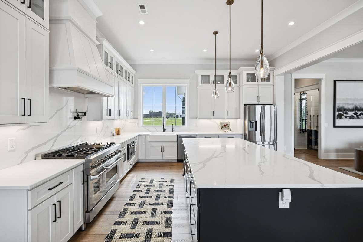 Gourmet kitchen featuring quartz countertops, custom cabinetry, and a professional-grade gas range. Large island with seating offers prep space and casual dining, while windows above the sink bring in natural light and scenic views.