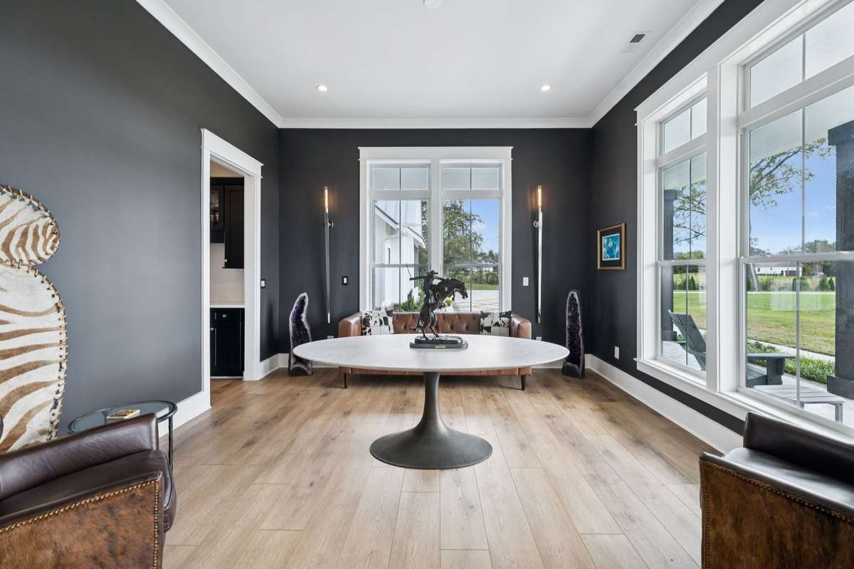 Formal dining room with large windows and views of the acreage, offering flexibility for gatherings or conversion to a private home office. Bold accent walls and natural light create a refined, versatile space.