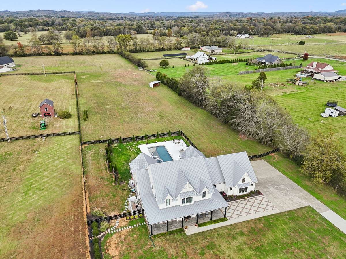 Expansive fenced acreage showcasing the home, pool, and private countryside setting.